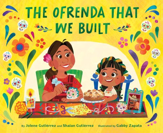 A yellow picture book cover depicting a smiling Latine woman and girl decorating an ofrenda for Día de Muertos using colorful candy skulls, candles, pan dulce, papel picado, flowers, and photos.